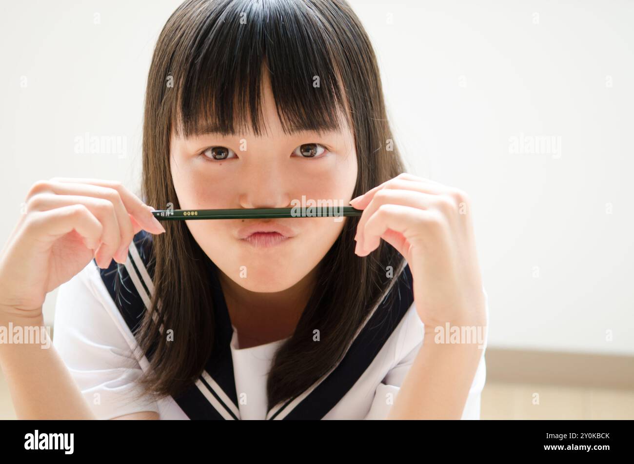 Ragazza in uniforme?tenendo una matita sotto il naso Foto Stock