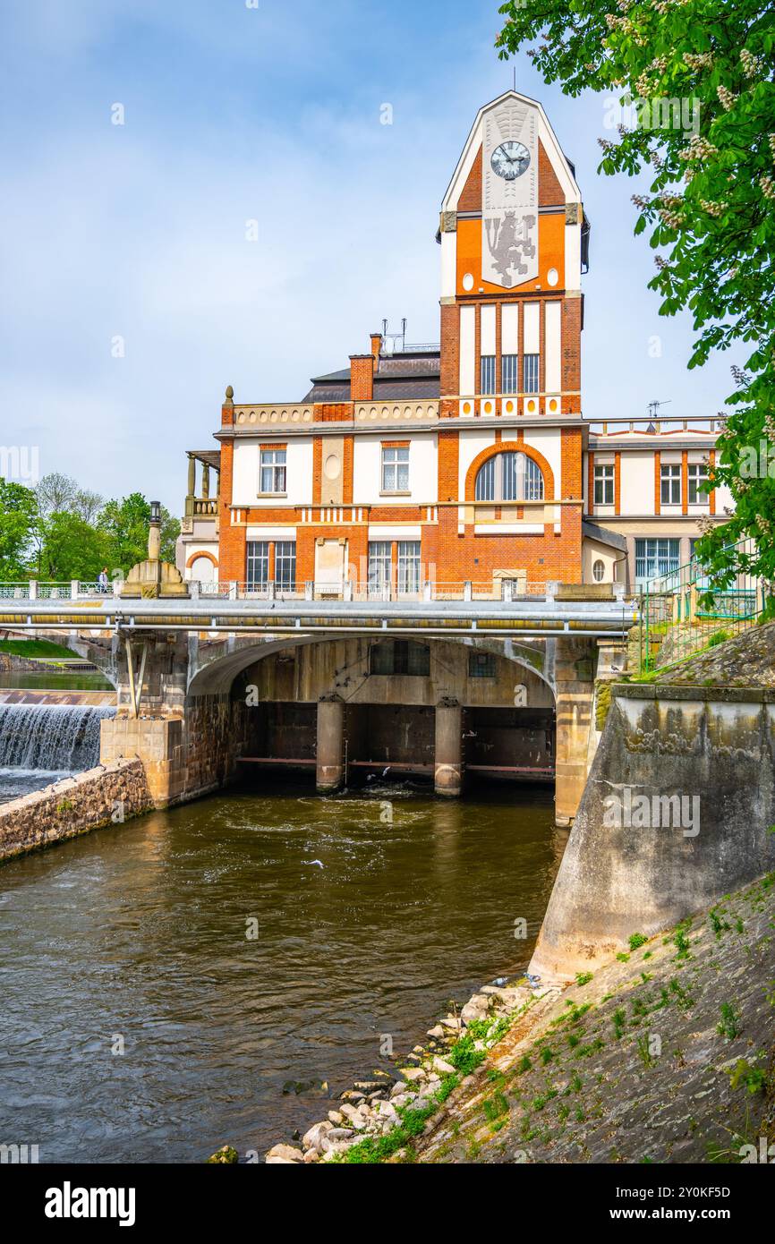La centrale idroelettrica di Hucak mostra la sua architettura Art Nouveau a Hradec Kralove, in Cechia, mentre l'acqua scorre sotto il suo ponte in una giornata limpida. Una miscela di natura e ingegneria storica. Foto Stock
