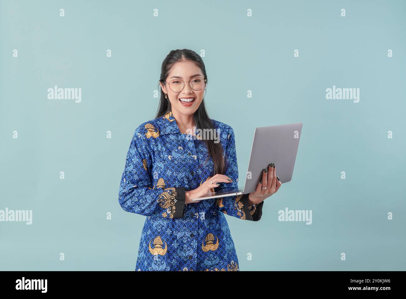Felice lavoratrice del governo indonesiano che tiene il suo laptop e sorride alla fotocamera. Concetto di funzionario pubblico PNS. Foto Stock