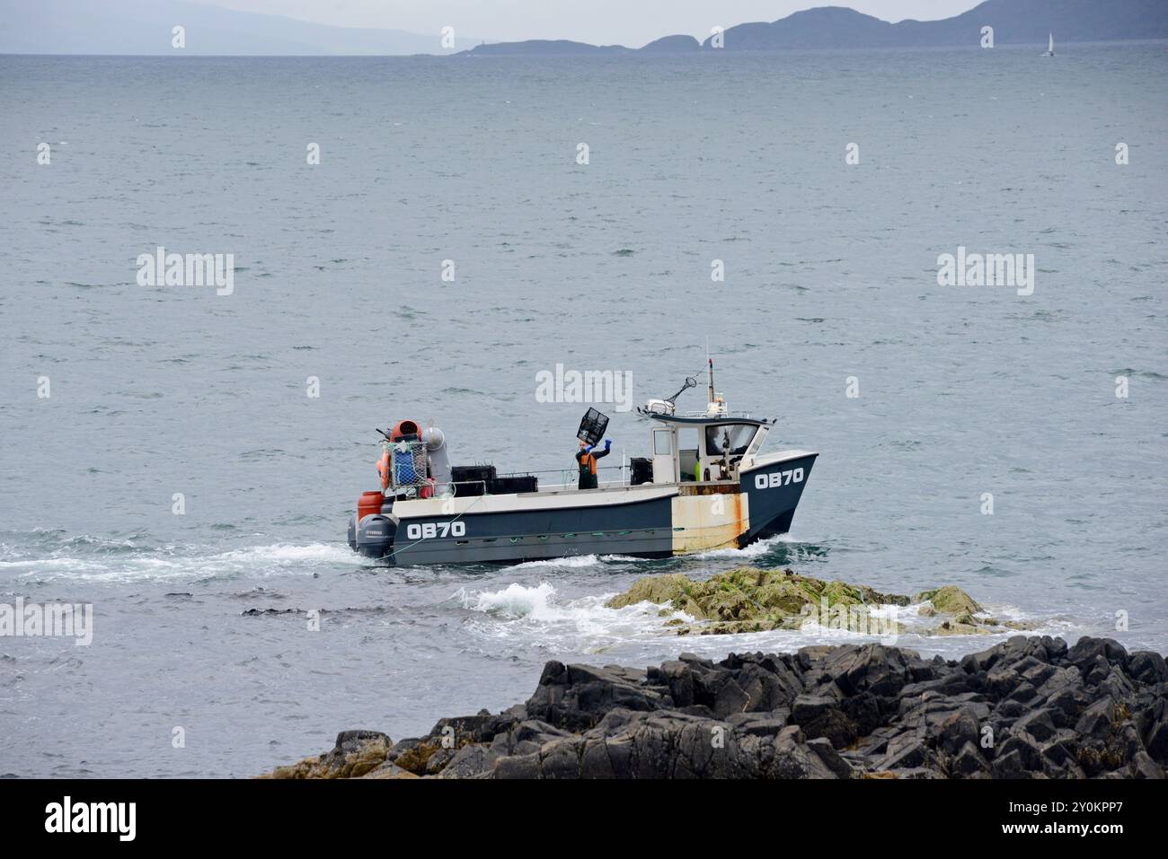 Un pescatore lancia in mare vasi di aragosta dalla barca da pesca Hunter 2, vicino a Mallaig, Scozia, luglio 2024 Foto Stock