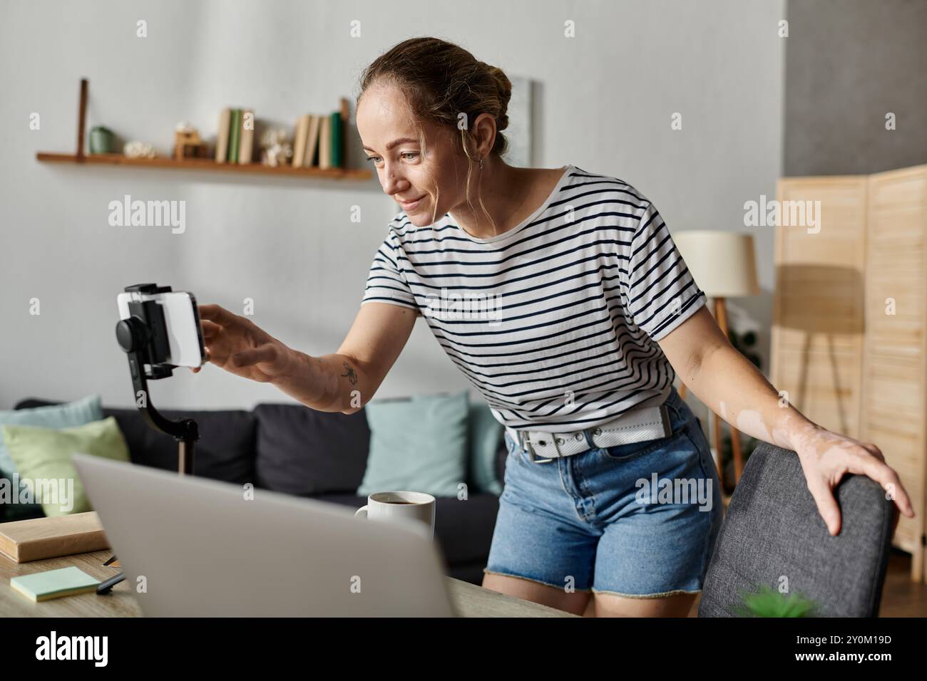 Una donna con vitiligine sorride mentre prepara la sua macchina fotografica per un nuovo progetto. Foto Stock