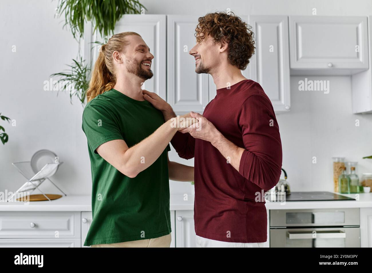 Due partner condividono un momento tenero mentre preparano un pasto nella loro accogliente cucina. Foto Stock