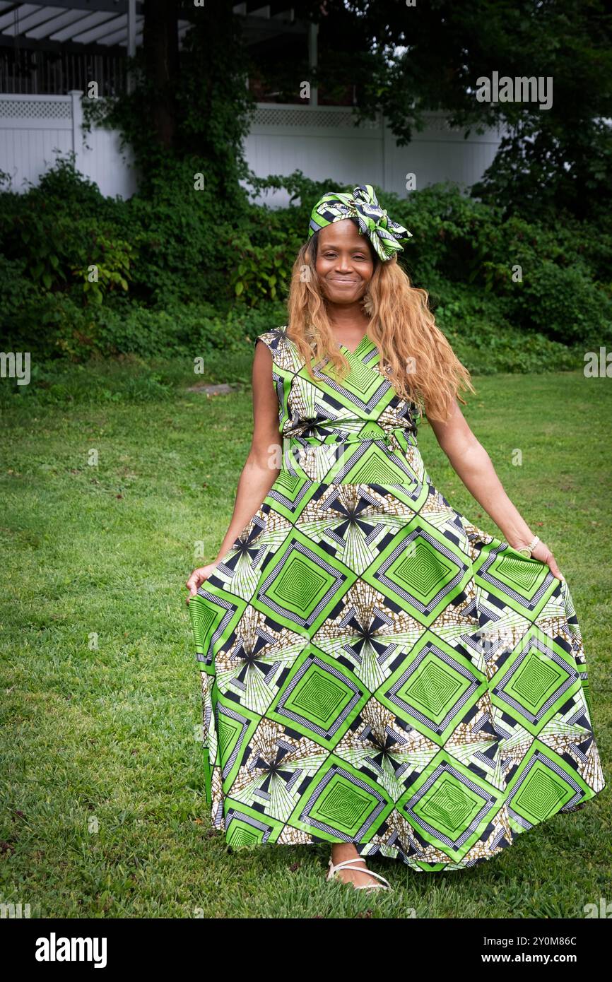 Una donna partecipante all'annuale Wakanda Celebration che indossa un caratteristico abito con motivi liberiani e un fiocco di capelli. A Mount Vernon, Westchester, New York. Foto Stock