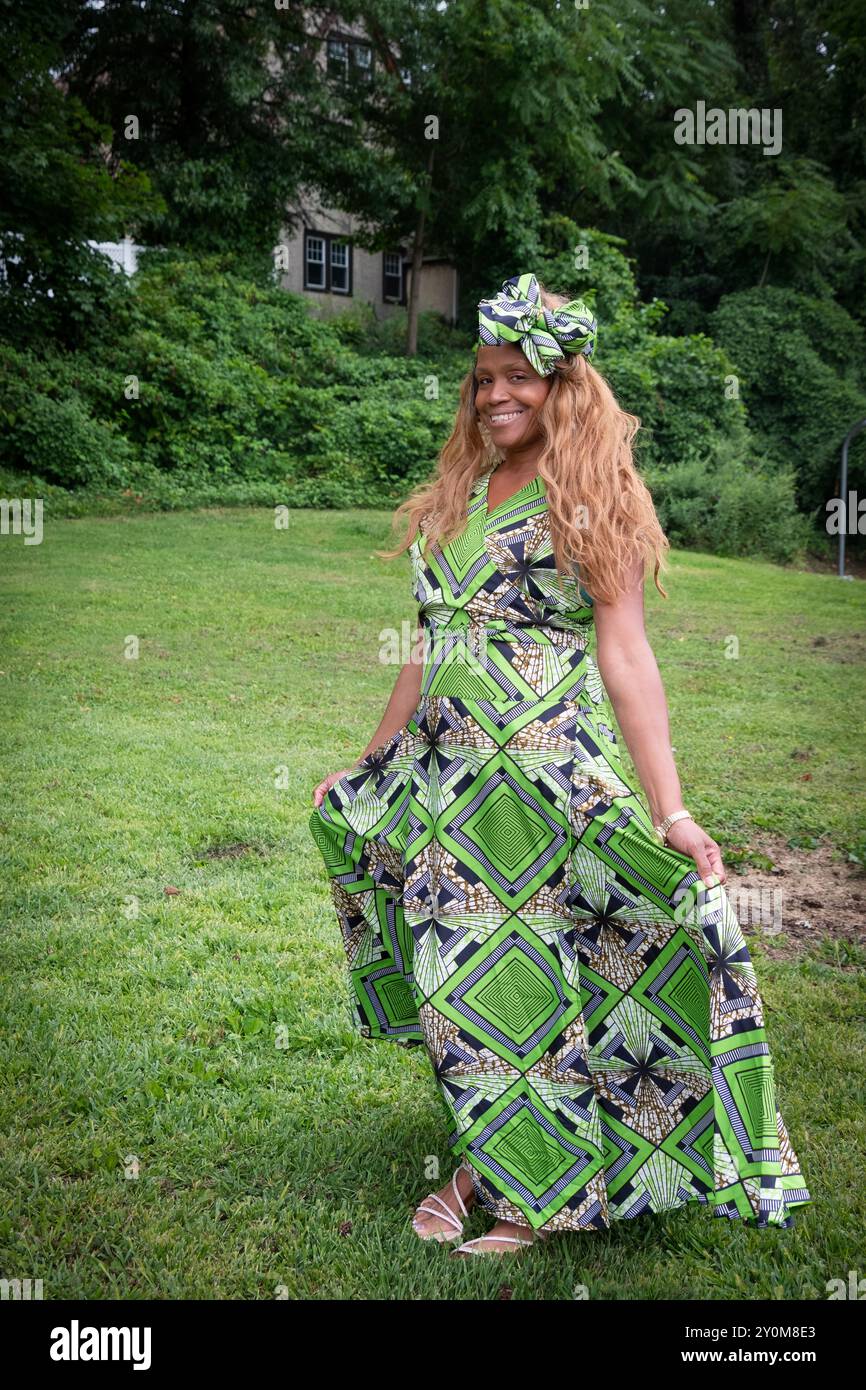Una donna partecipante all'annuale Wakanda Celebration che indossa un caratteristico abito con motivi liberiani e un fiocco di capelli. A Mount Vernon, Westchester, New York. Foto Stock