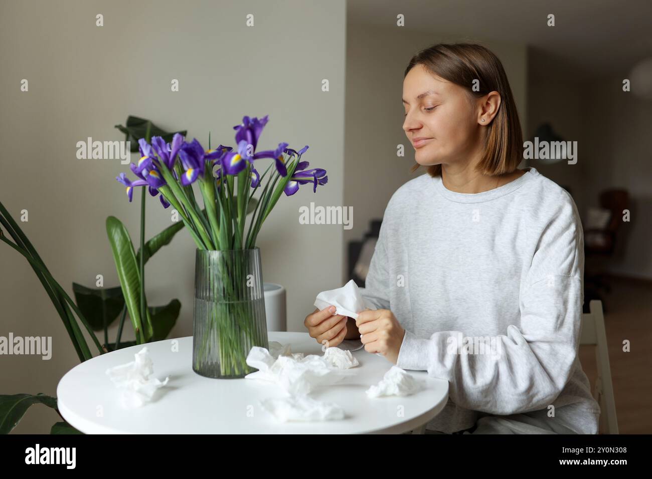 Stagionale, senza allergie. Giovane donna sniff di fiori di Iris, gode di odore senza di naso che cola, prurito o tosse sintomi stagionali a casa accogliente. GIR Foto Stock