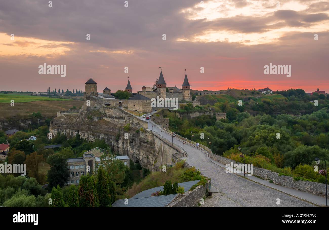 Panorama al tramonto del castello medievale di Kamianets-Podilskyi. Bellissimo e famoso castello su una penisola rocciosa nel canyon del fiume Smotrych al crepuscolo Foto Stock