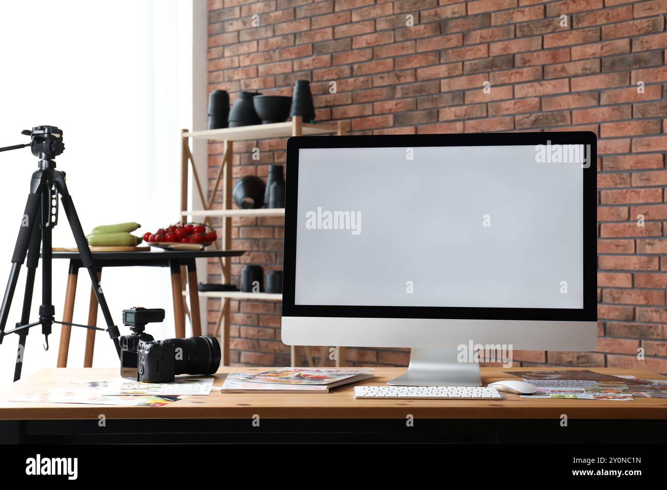 Computer, macchina fotografica, riviste e verdure sul tavolo in studio. Fotografia gastronomica Foto Stock