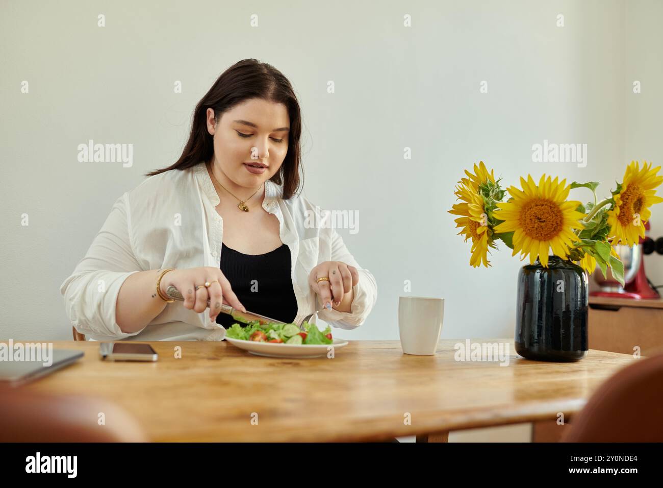 Una donna allegra assapora un pasto sano mentre è circondata da girasoli. Foto Stock