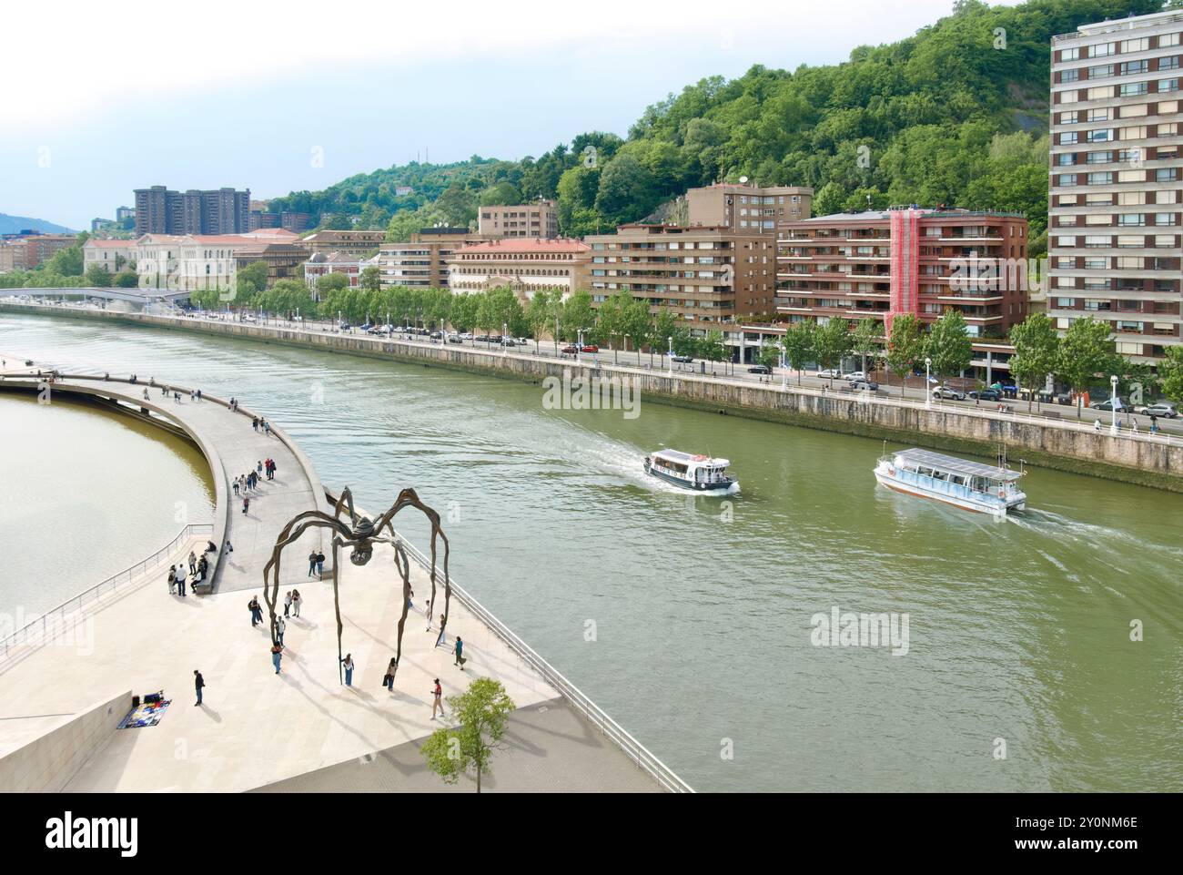 Scultura di ragno Maman alta 9 metri fuori dal Museo d'Arte Guggenheim con barche turistiche che passano per il fiume Nervion Bilbao Paesi Baschi Euskadi Spagna Foto Stock