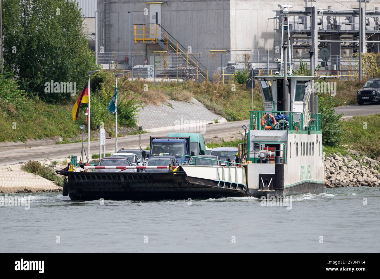 , Deutschland, 03.09.2024, Die Rheinfähre 'Altrip-Mannheim' überquert den Fluss, beladen mit Fahrzeugen, vor dem Hintergrund eines Industriekomplexes Foto Stock