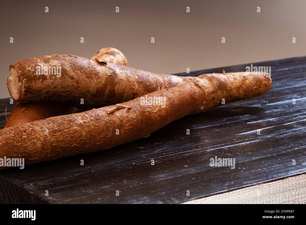 Radici di manioca con buccia sopra un buio. Foto Stock