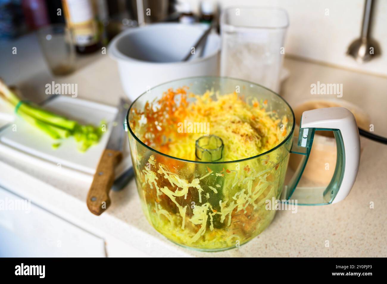 Verdure crude grattugiate (patate, carote, zucchine) su un grande recipiente sul tavolo da cucina. Pasto di preparazione. Foto Stock