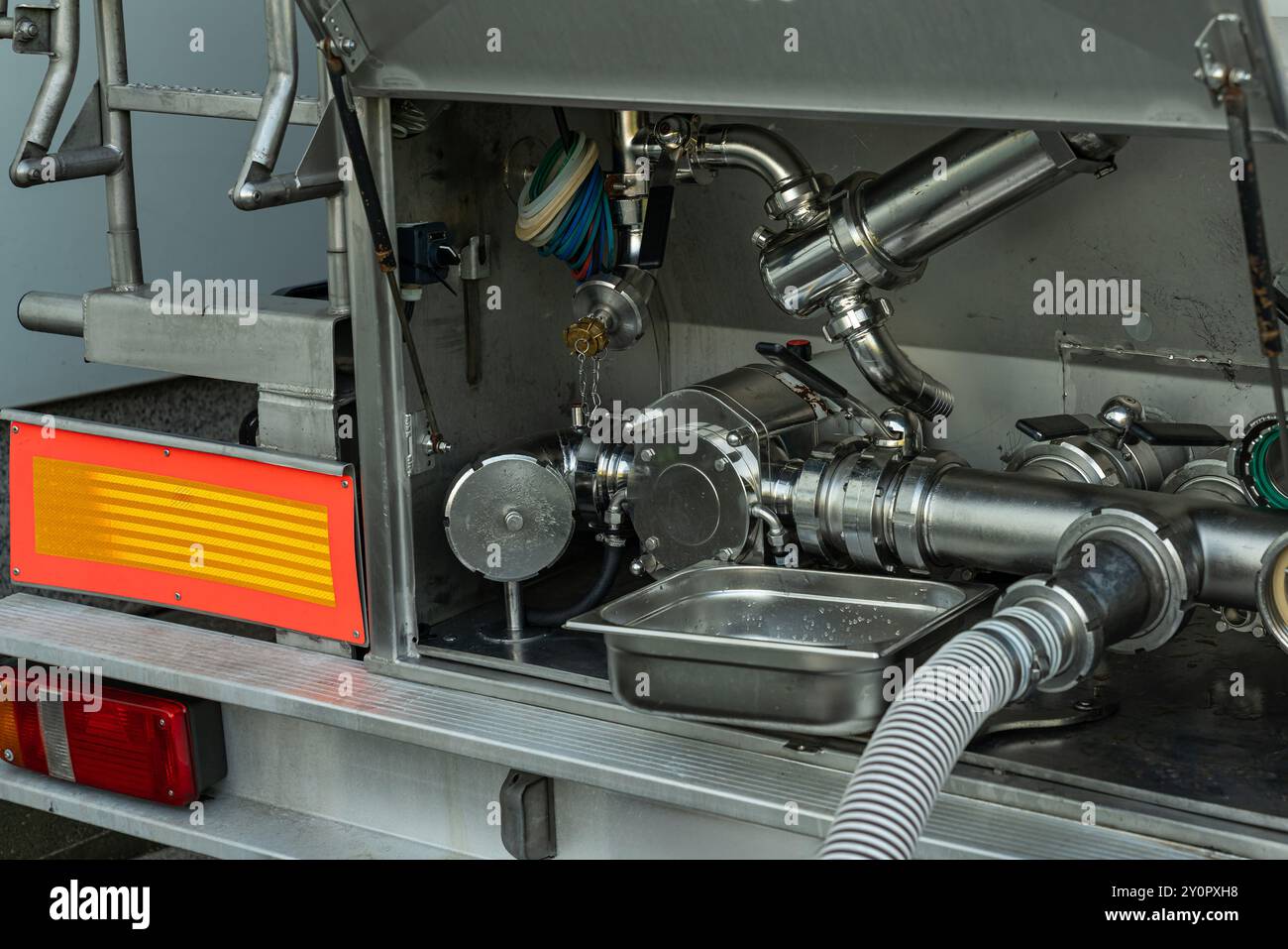 Un primo piano dettagliato della valvola e del sistema di tubazioni su un'autocisterna, utilizzato per controllare e trasferire il contenuto di liquidi durante la consegna. Foto Stock