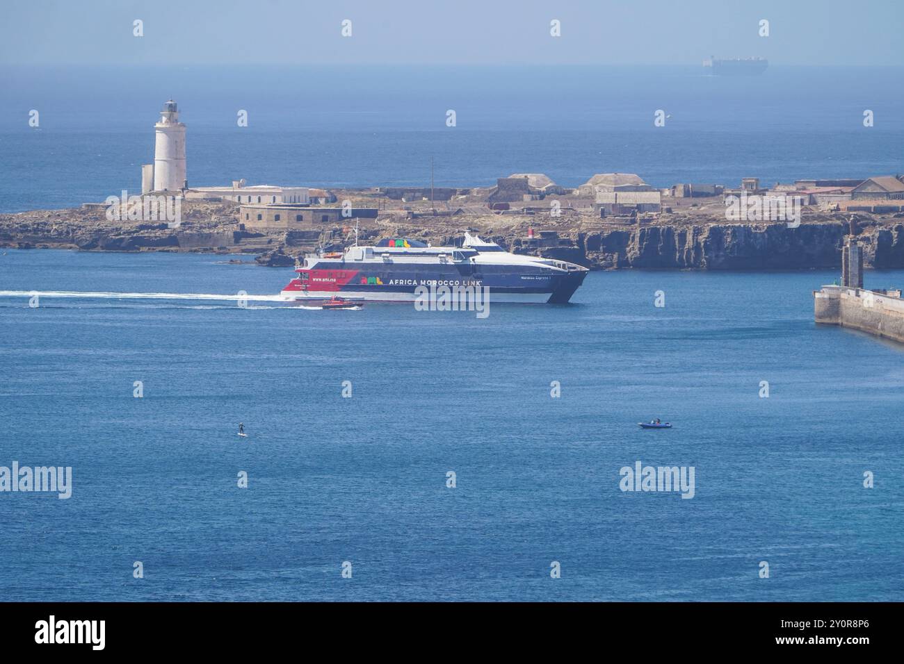 Faro del XVIII secolo a Tarifa Point, con traghetto in arrivo nel porto, Andalusia, Spagna. Foto Stock