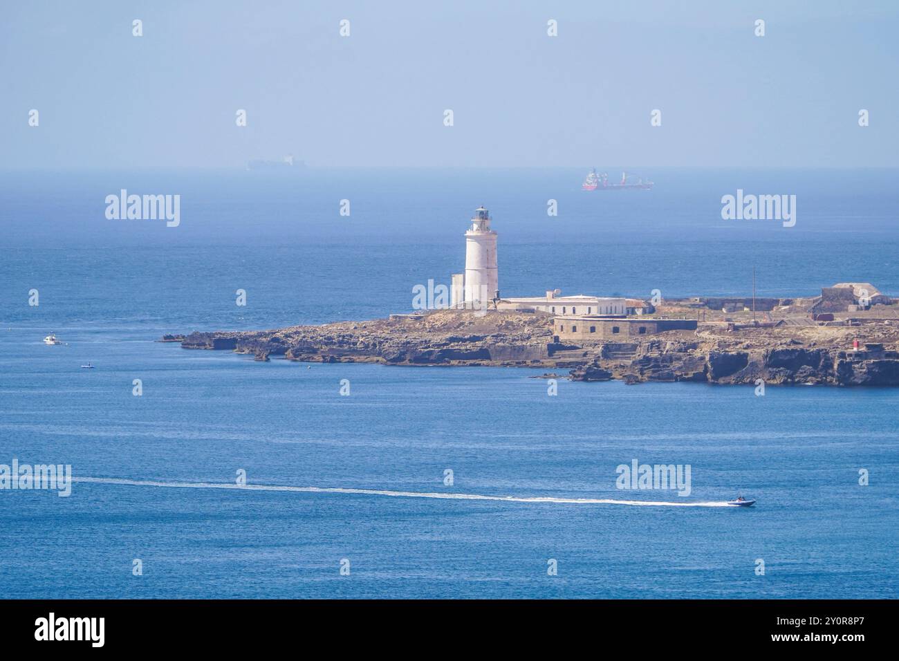 Faro del XVIII secolo a Tarifa Point, con traghetto in arrivo nel porto, Andalusia, Spagna. Foto Stock