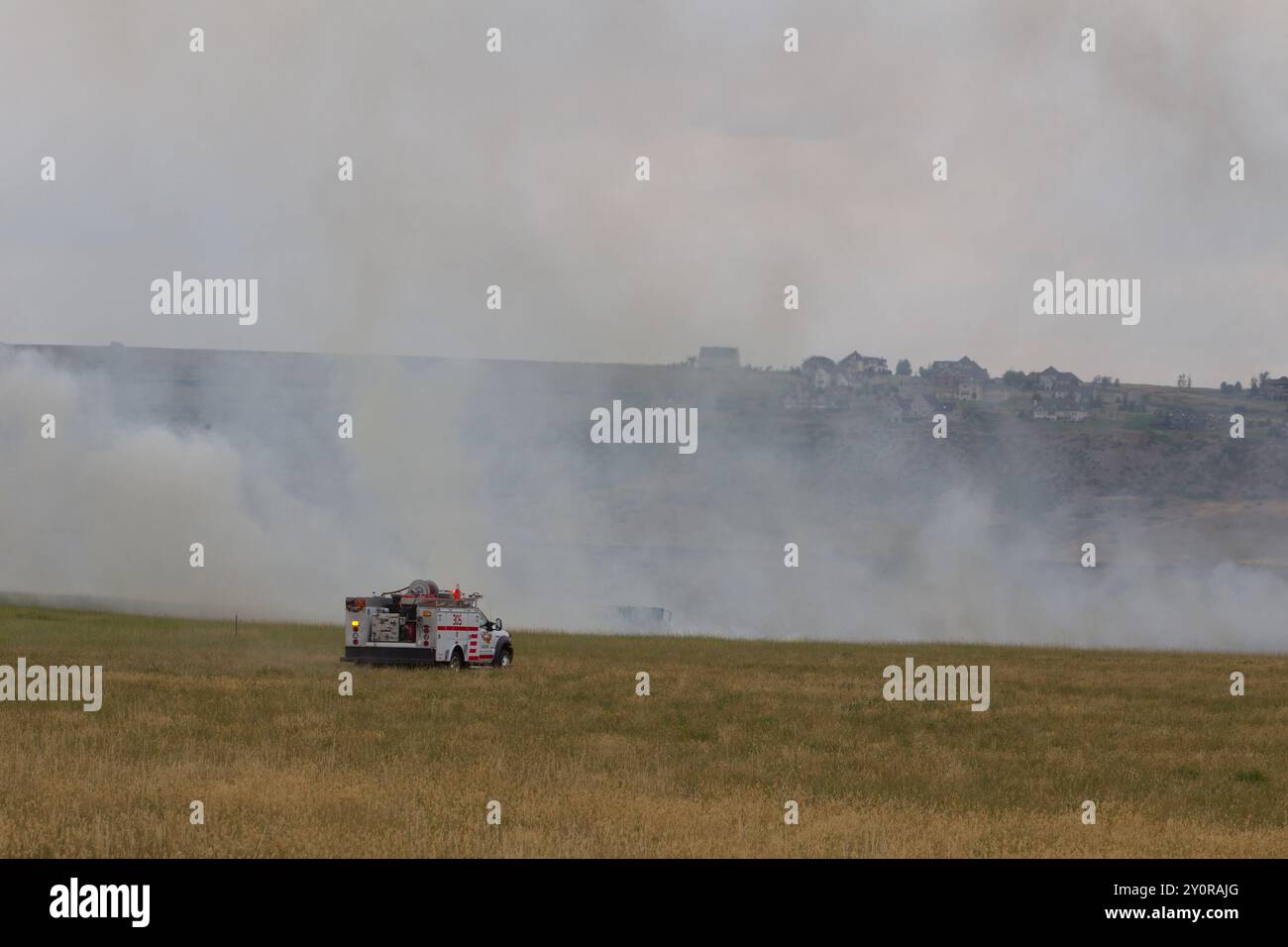 Un equipaggio dei vigili del fuoco della città risponde a un incendio in erba che viene combattuto da un dipartimento dei vigili del fuoco volontario locale. I vigili del fuoco rurali sono di solito volontari. Foto Stock
