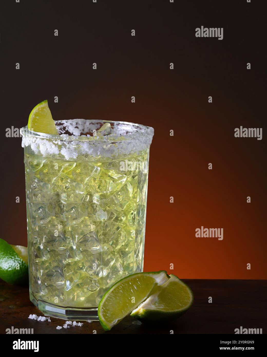 Un margarita sulle rocce in un bicchiere di vetro. Su un tavolo di legno scuro con uno sfondo chiaro-scuro con spazio di copia. Foto Stock