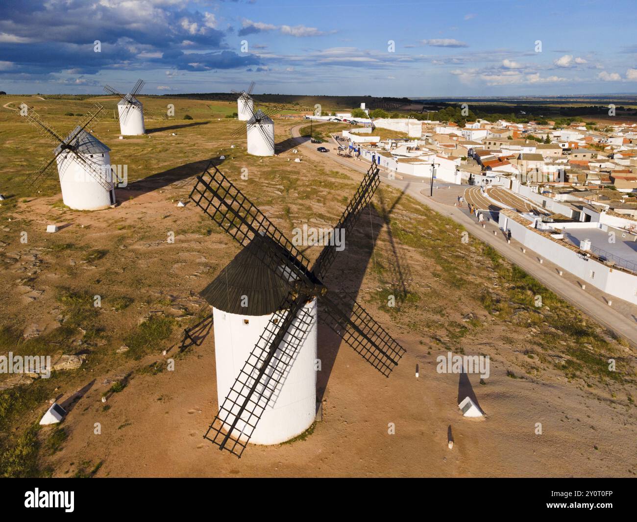 Mulini a vento in un ambiente rurale con clima soleggiato con cielo blu e nuvole. Sullo sfondo un villaggio con case bianche e tetti rossi. Vista aerea, vento Foto Stock