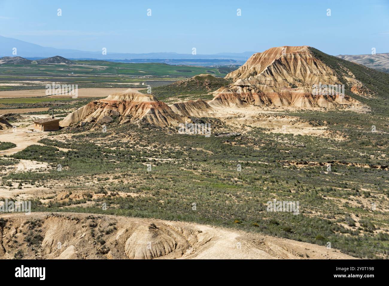 Vasto paesaggio desertico con impressionanti formazioni rocciose e vegetazione sparsa sotto un cielo limpido, parco naturale Bardenas Reales, deserto, semi-deserto, Navarr Foto Stock