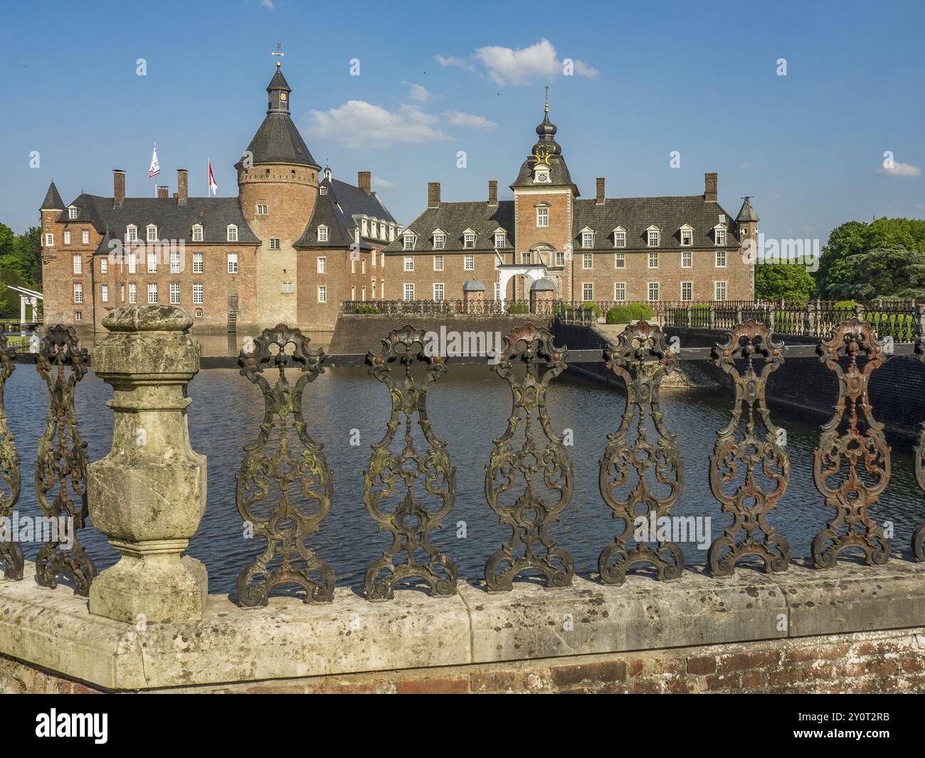 Castello storico con fossato e recinzione a reticolo ornato, paesaggio verde e cielo luminoso, Anholt, Renania settentrionale-Vestfalia, Germania, Europa Foto Stock