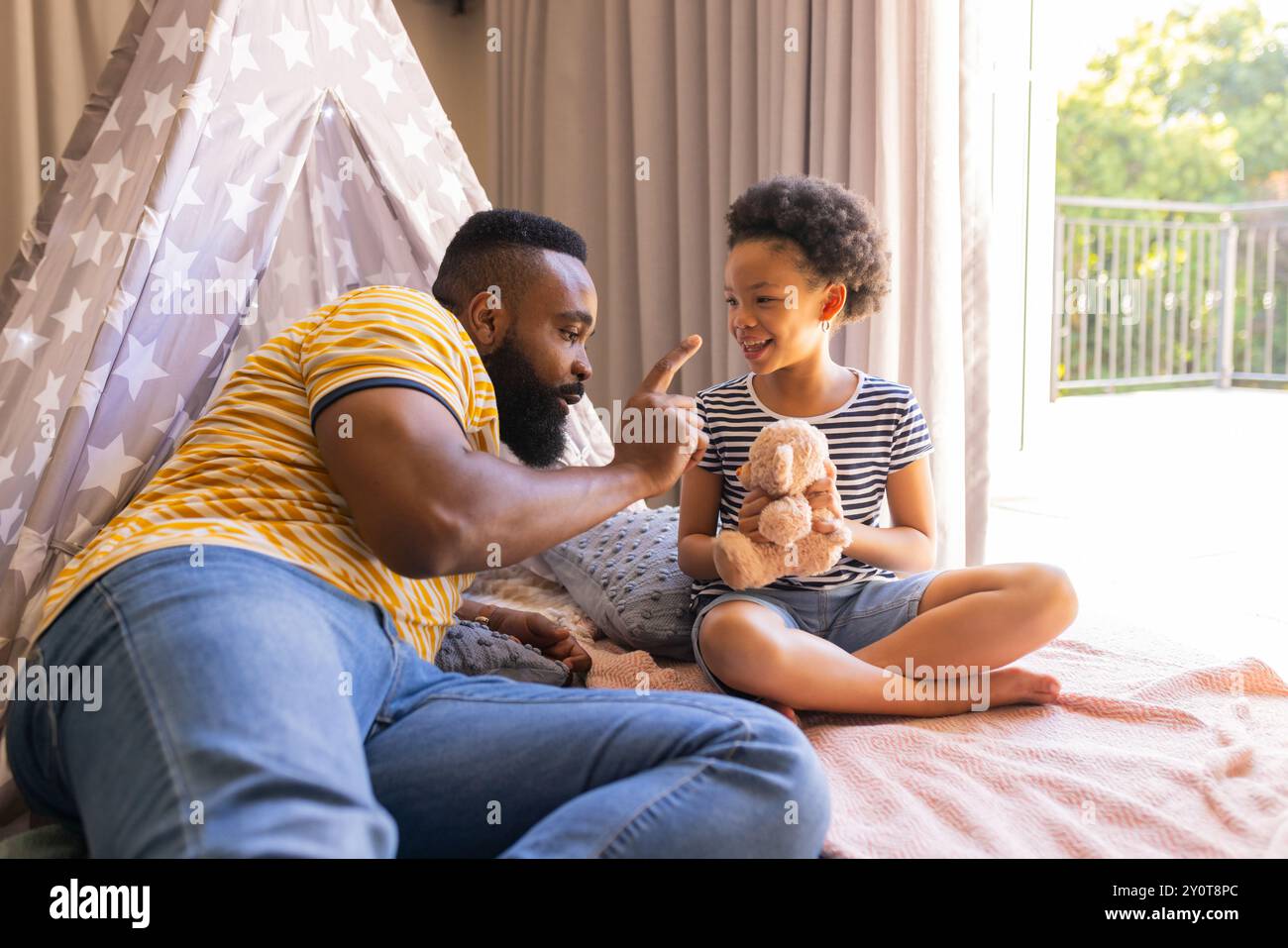 Giocando con animali ripieni, padre e figlia che si legano in un ambiente accogliente, in teepee Foto Stock