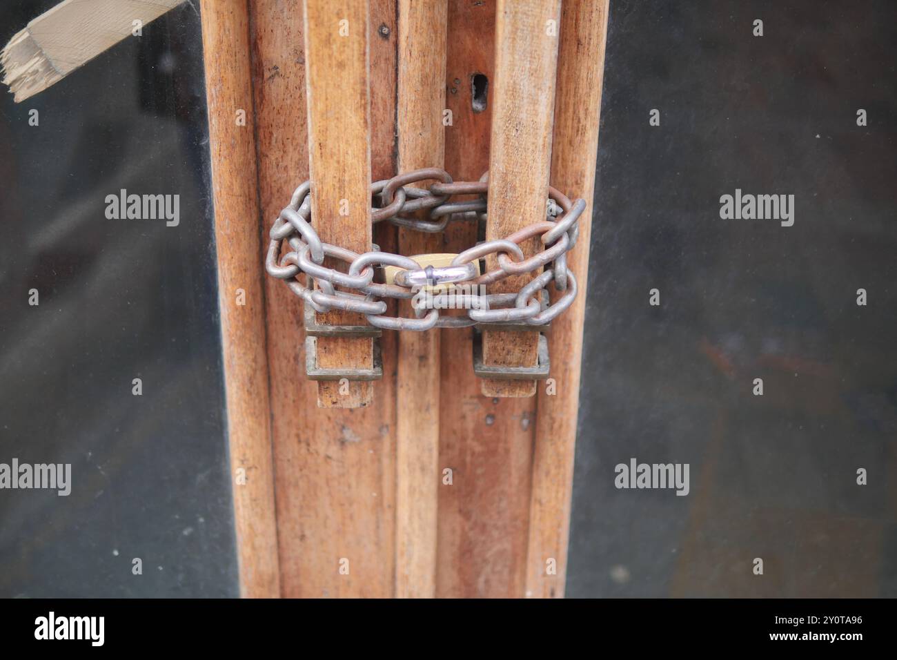 Un set di porte in legno bloccate con una robusta catena e un robusto lucchetto per la sicurezza Foto Stock
