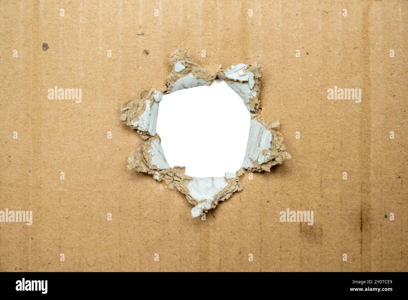 Un foro in una scatola di cartone. Il foro è grande e ha uno sfondo bianco Foto Stock