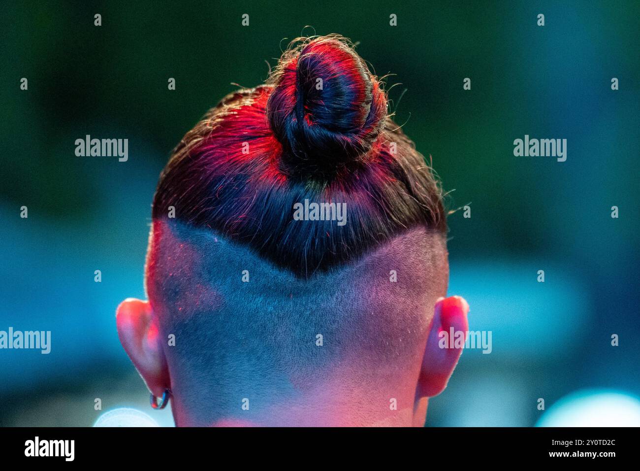 Primo piano sul palcoscenico: Primo piano dell'acconciatura Single Bun di Young Man: Rasatura parziale, prestazioni notturne. Foto Stock