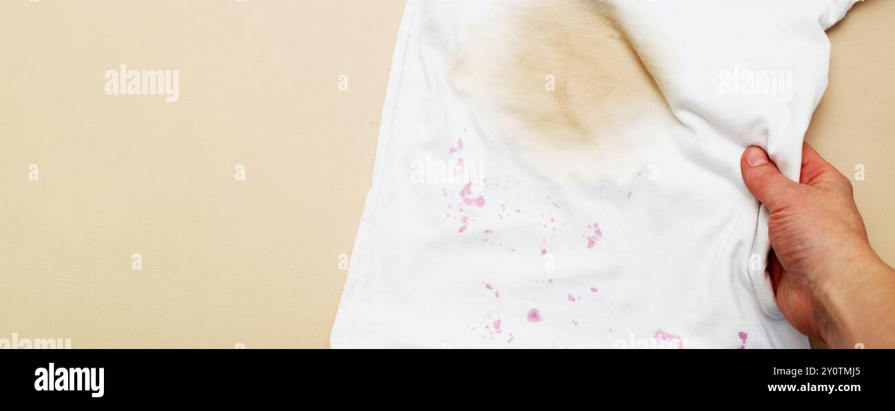 Macchie sporche su una T-shirt bianca da bacche e bere su sfondo marrone. Foto Stock