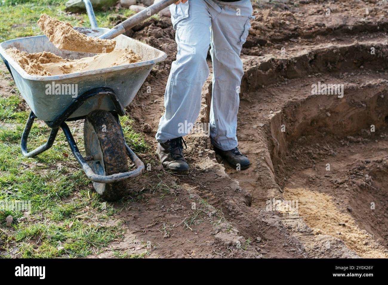 Uomo che usa la sabbia per ammorbidire le terrazze di uno stagno. Foto Stock