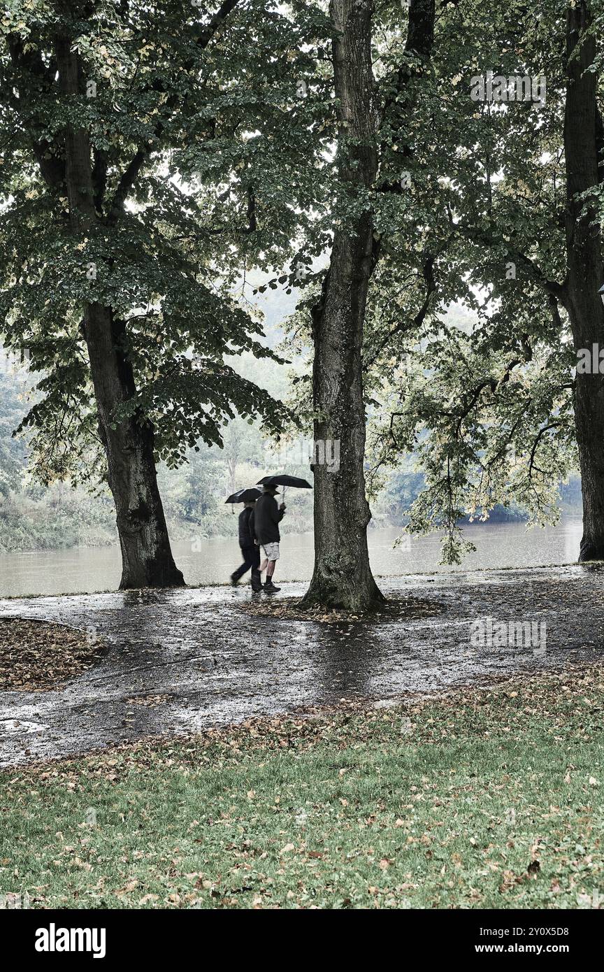 Coppia sotto ombrelloni camminando sotto la pioggia lungo il fiume Ribble a Preston Foto Stock Coppia sotto ombrelloni camminando sotto la pioggia lungo il fiume Ribble a Preston Foto Stock