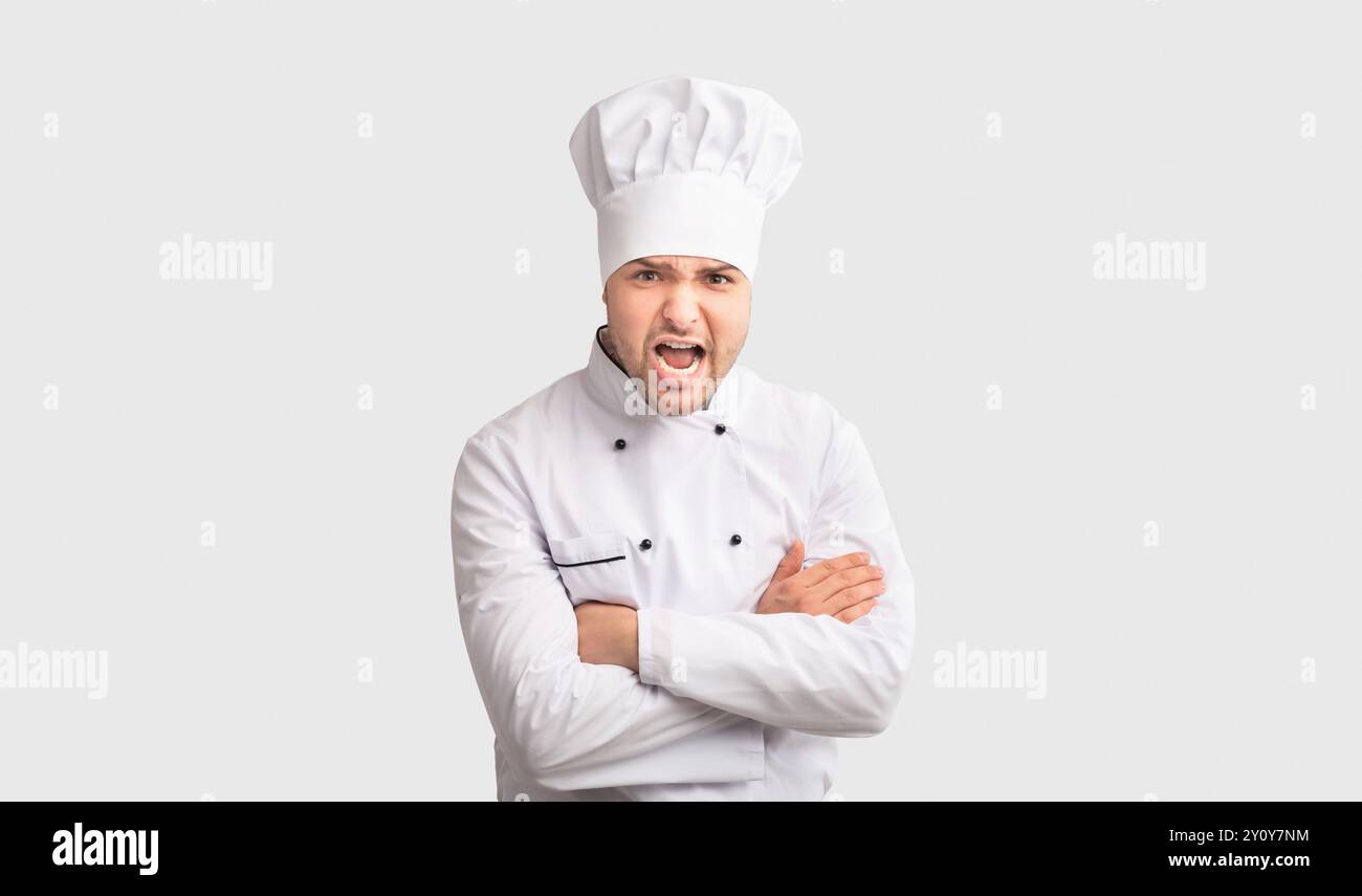Arrabbiato Chef uomo grida attraversando le mani in piedi in studio, Panorama Foto Stock