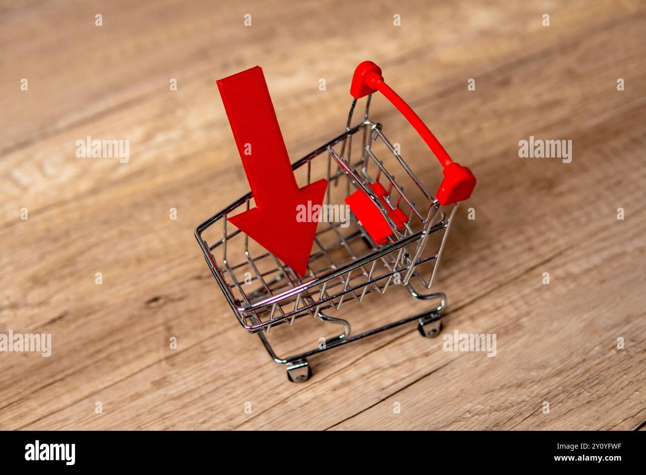 Carrello in miniatura con freccia rossa rivolta verso il basso. Tendenze al dettaglio, calo delle vendite, concept di calo delle vendite. Foto Stock