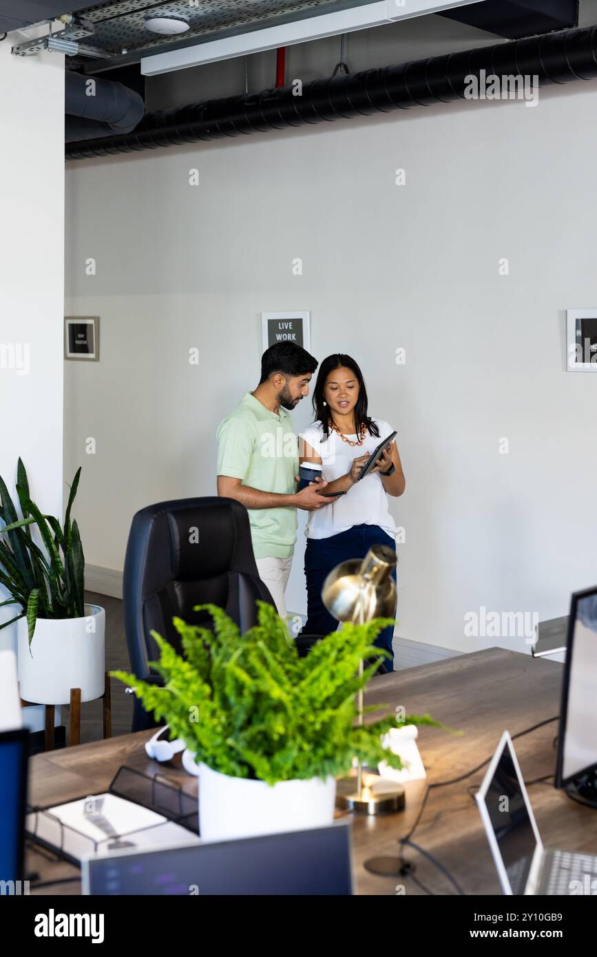 Discussione dei dettagli del progetto, colleghi che utilizzano un tablet in un ufficio moderno con impianti, copia dello spazio Foto Stock