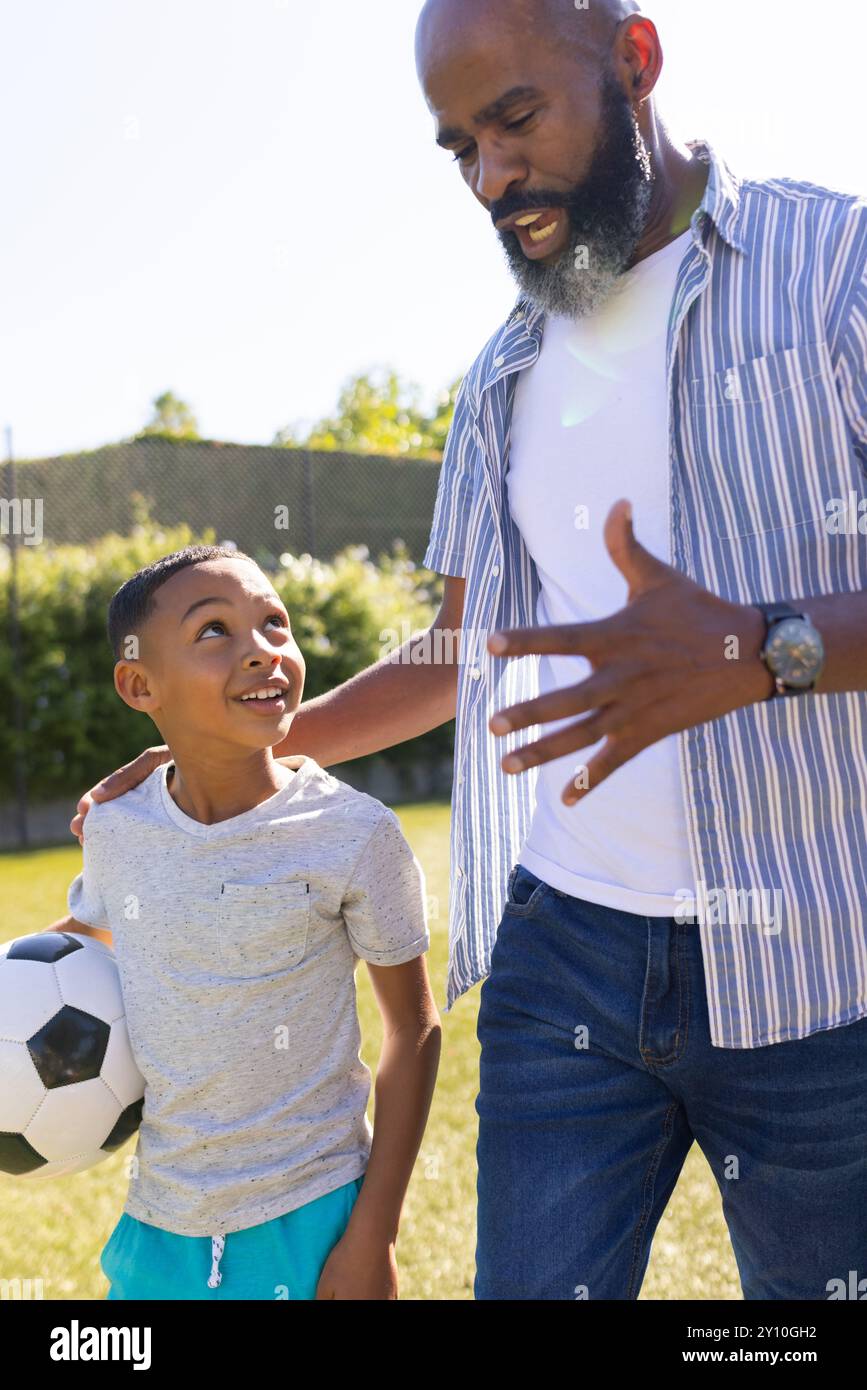 Nonno e nipote si uniscono, tengono un pallone da calcio e parlano all'aperto Foto Stock