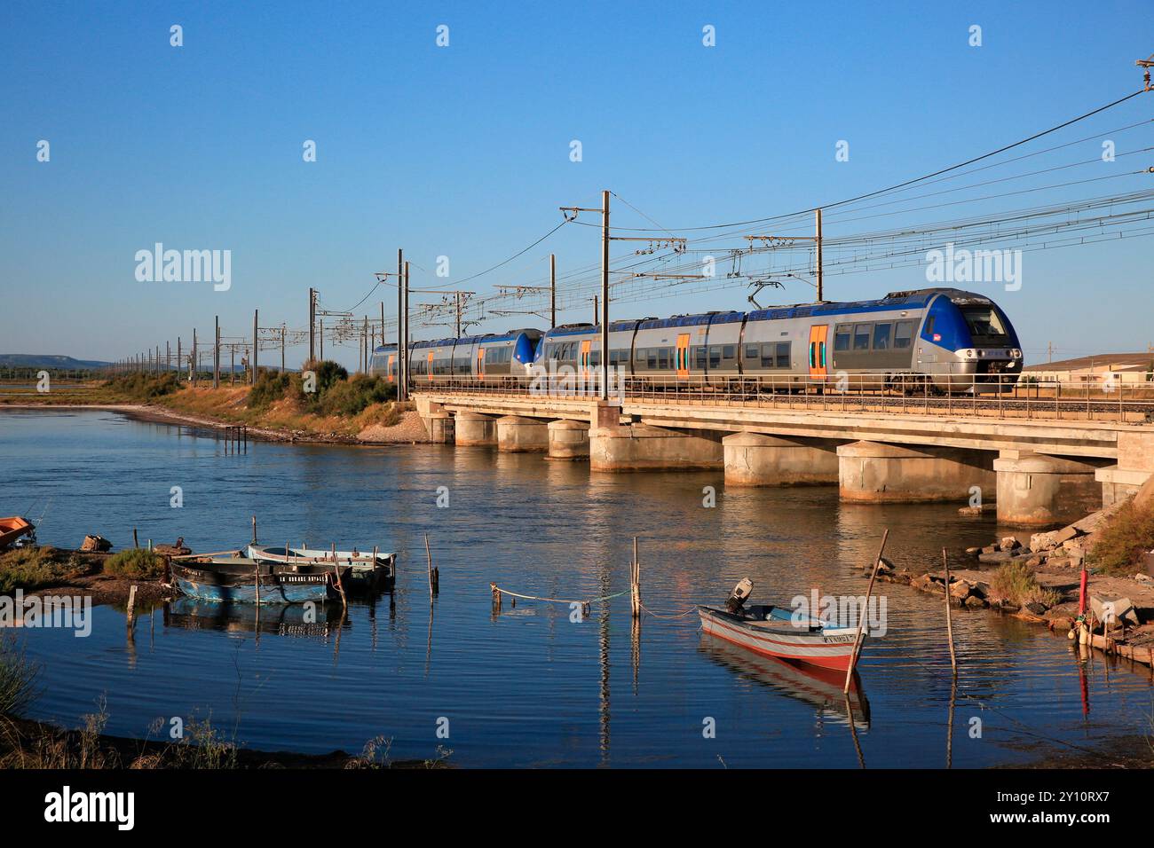 La linea principale dalla Francia alla Spagna corre tra Narbona e Perpignano in Francia diverse volte lungo le Etangs e le spiagge. A Port-la-Nouvelle, un treno locale per Portbou in Spagna sta attraversando il ponte del porto. I vagoni ferroviari corrono tra Montpellier e la stazione di confine spagnola di Portbou. Foto Stock