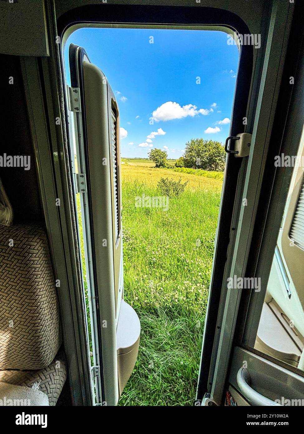 Vista dall'interno del moderno parcheggio camper in camper nel verde della campagna, luogo panoramico e vista del paesaggio. Viaggio in libertà, vacanza in casa alternativa, stile di vita vanlife Foto Stock