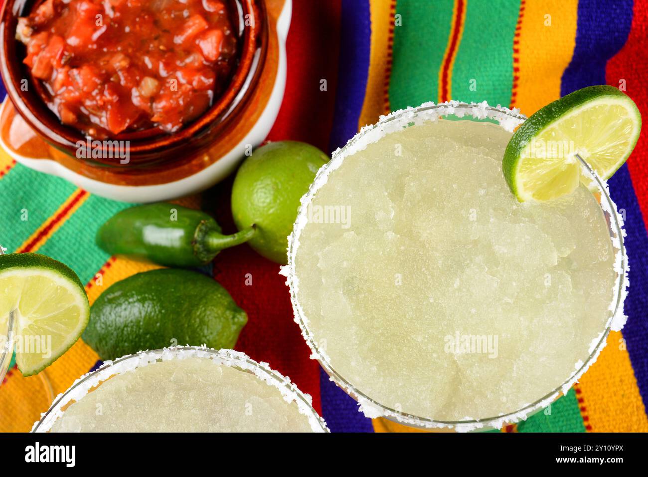 Concetto Cinco de Mayo: Margaritas e salsa su un panno colorato, con limes e peperoni. Foto Stock