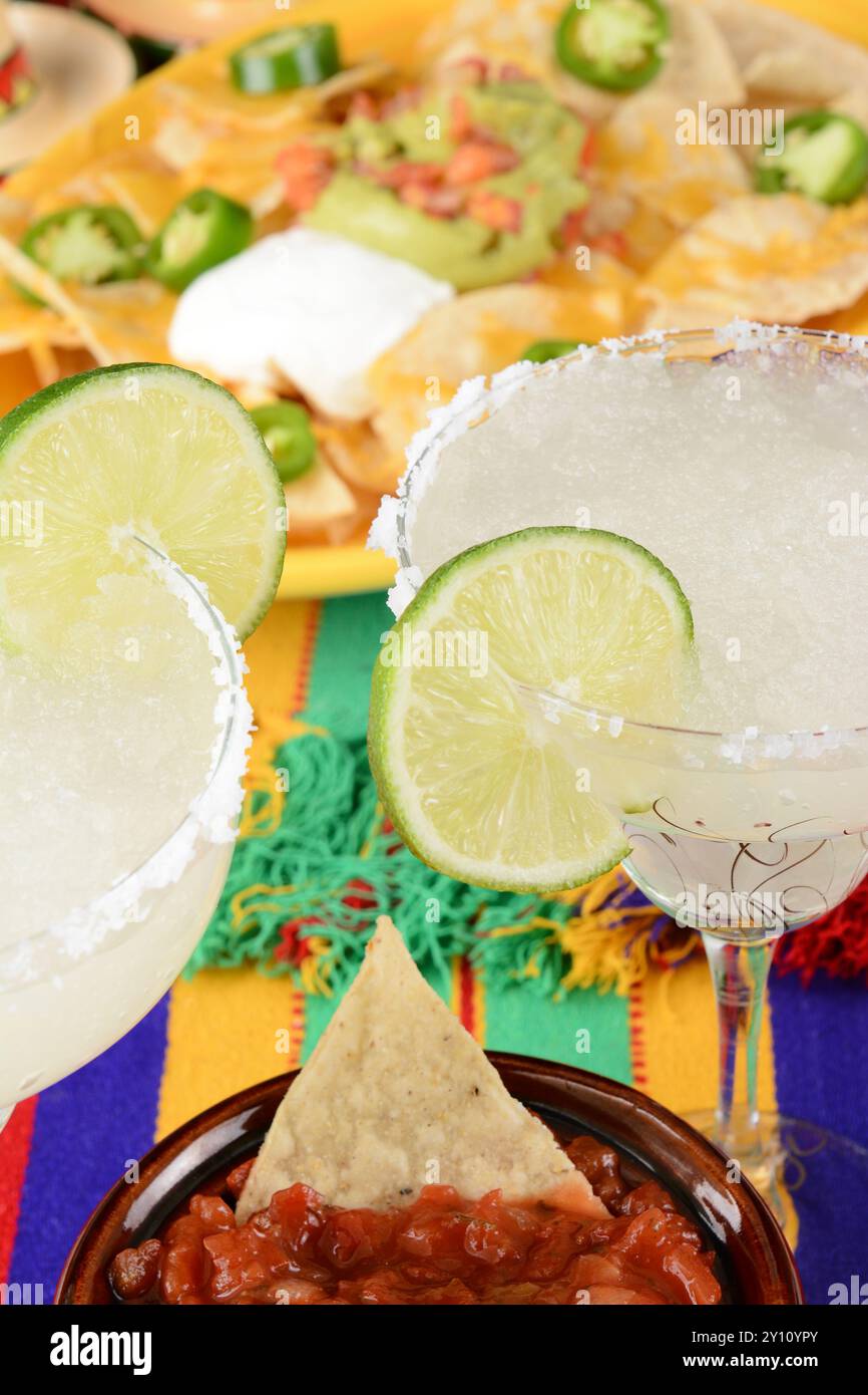 Concetto Cinco de Mayo: Margaritas e cibo messicano su un colorato panno da tavola, con nachos e salsa. Foto Stock