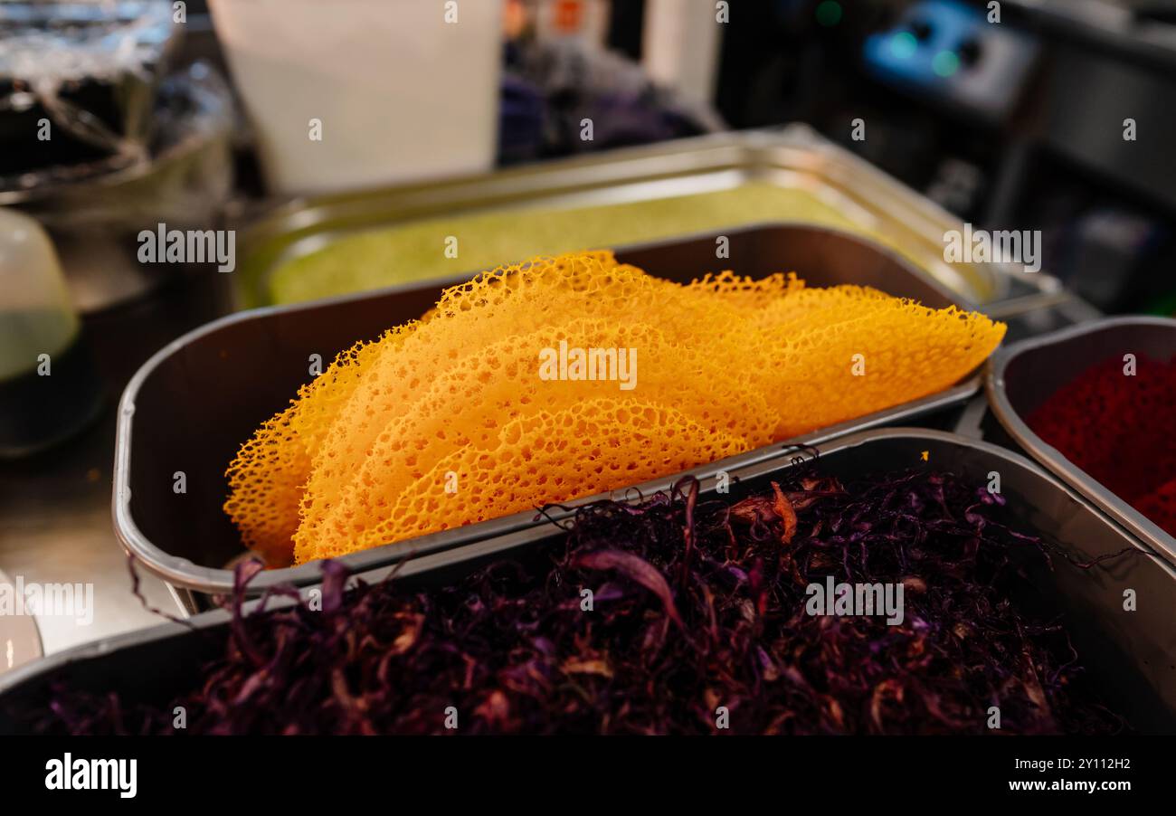 Primo piano di trippa gialla a nido d'ape e alghe dulse viola in contenitori metallici in cucina Foto Stock