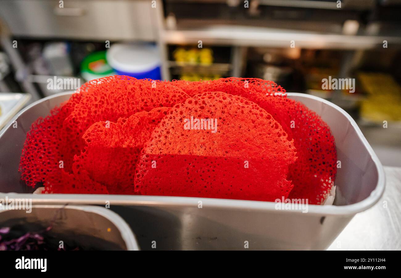 Cibo rosso simile a un pizzo in un contenitore metallico sul bancone della cucina Foto Stock