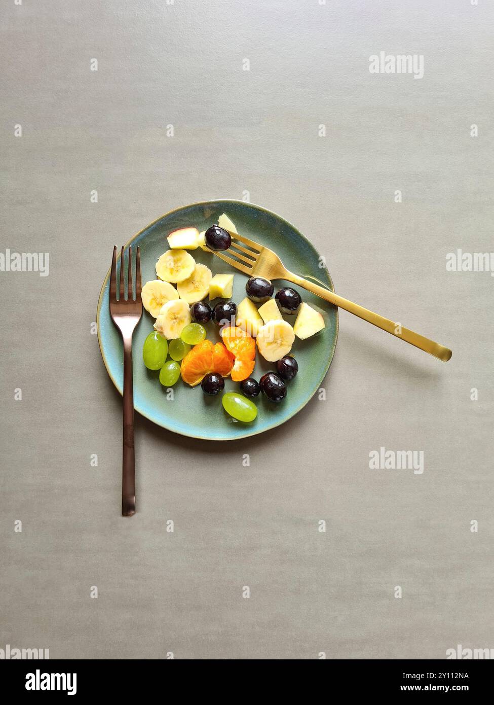 Frutta fresca su un piatto blu-verde, nutrizione ricca di vitamine, diversi tipi di frutta fresca sana servita come Macedonia di frutta o spuntino con due forchette diverse Foto Stock