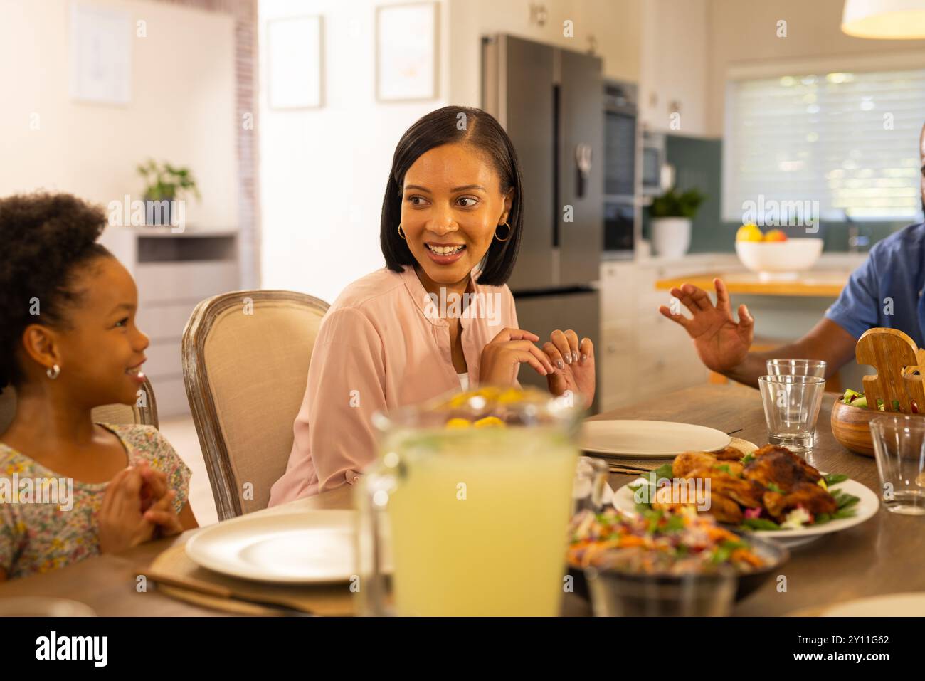 Famiglia sorridente, cena insieme, condivisione di storie e legame a casa Foto Stock