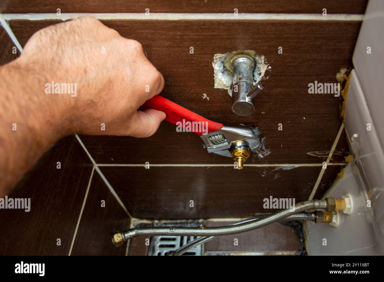 Idraulico che rimuove il rubinetto nel gabinetto in primo piano Foto Stock