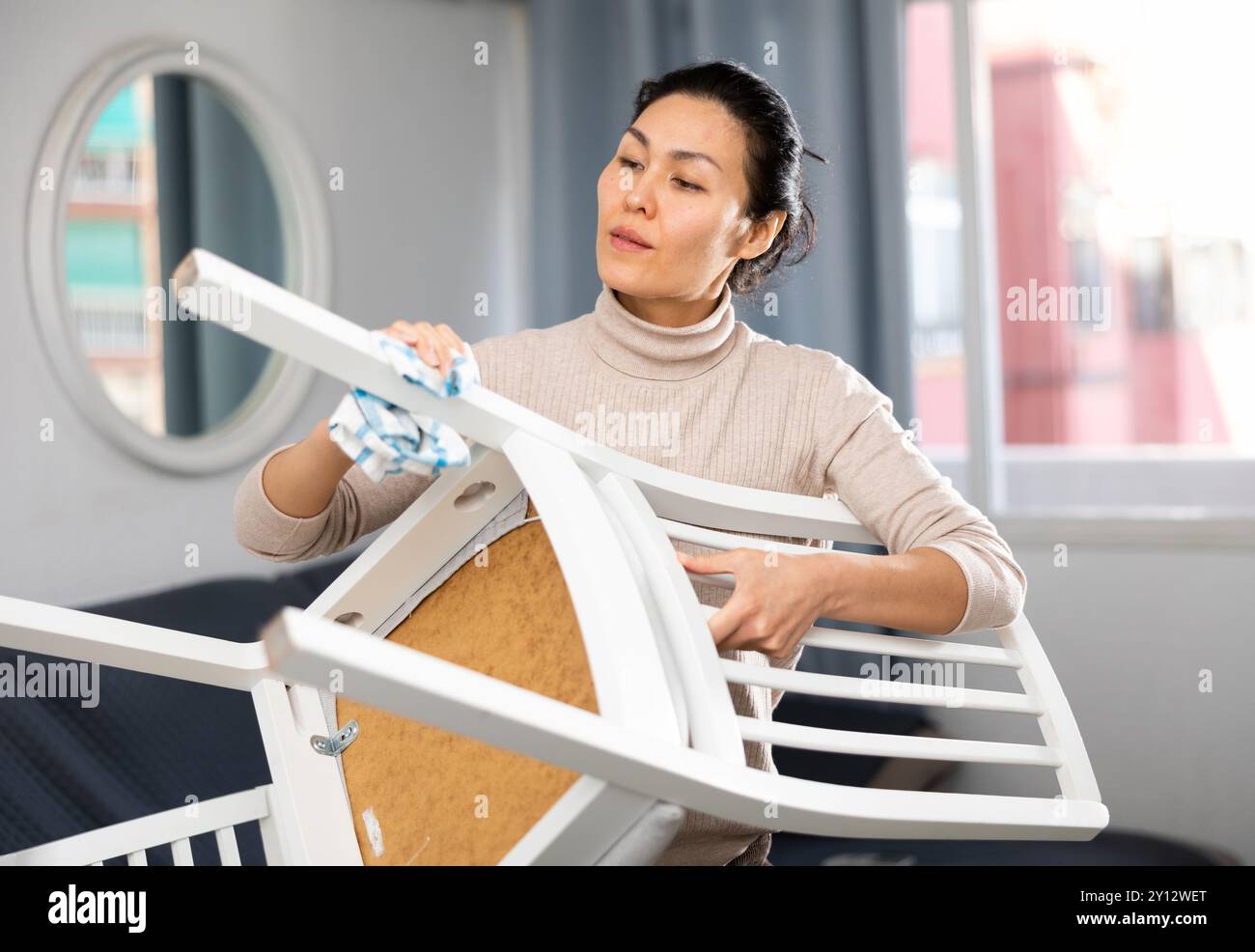 Donna asiatica asciuga una sedia con un panno umido Foto Stock