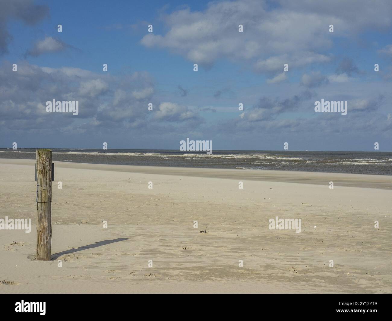 Spiaggia vuota con un solo palo e nuvole nel cielo, spiekeroog, frisia orientale, mare del nord, germania Foto Stock