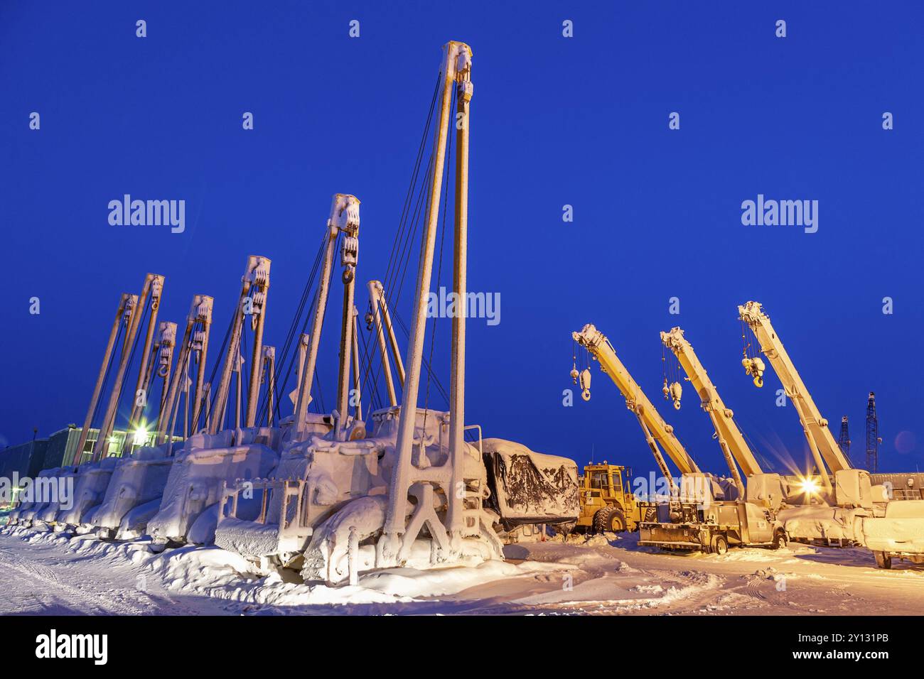 Gru e attrezzature per la produzione di petrolio nella neve, al crepuscolo, Deadhorse, Alaska, USA, nord America Foto Stock