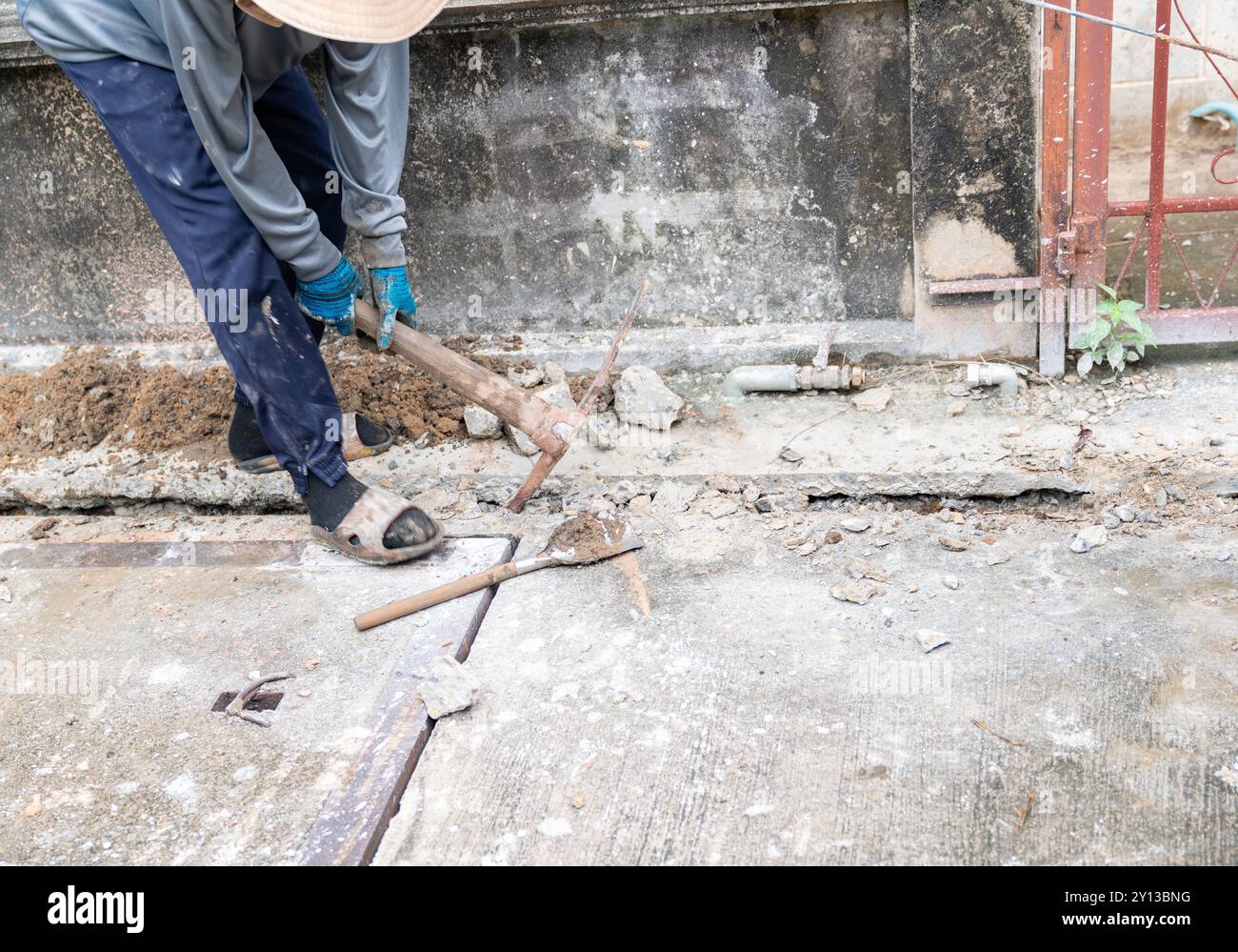 Un uomo prende terreno duro con un piccone in cantiere Foto Stock