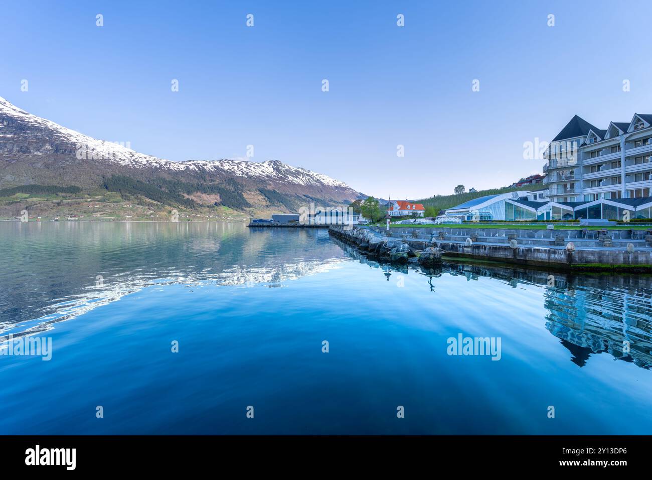 Un tranquillo villaggio adagiato sulla costa dell'Hardangerfjord. Il contrasto tra le case bianche e le calme acque turchesi è impressionante. Voss, Foto Stock