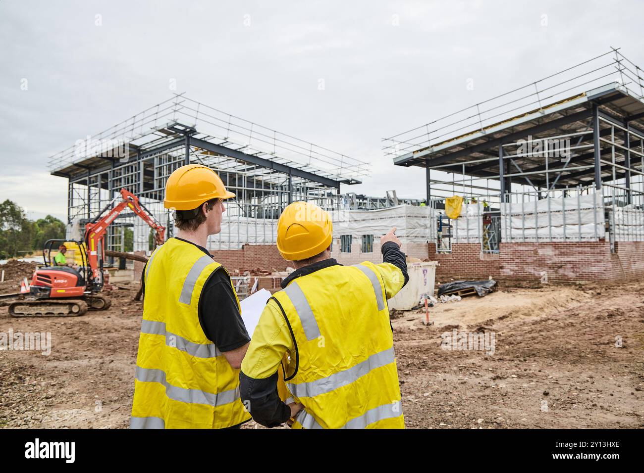 operai edili in cantiere che indossano indumenti protettivi Foto Stock